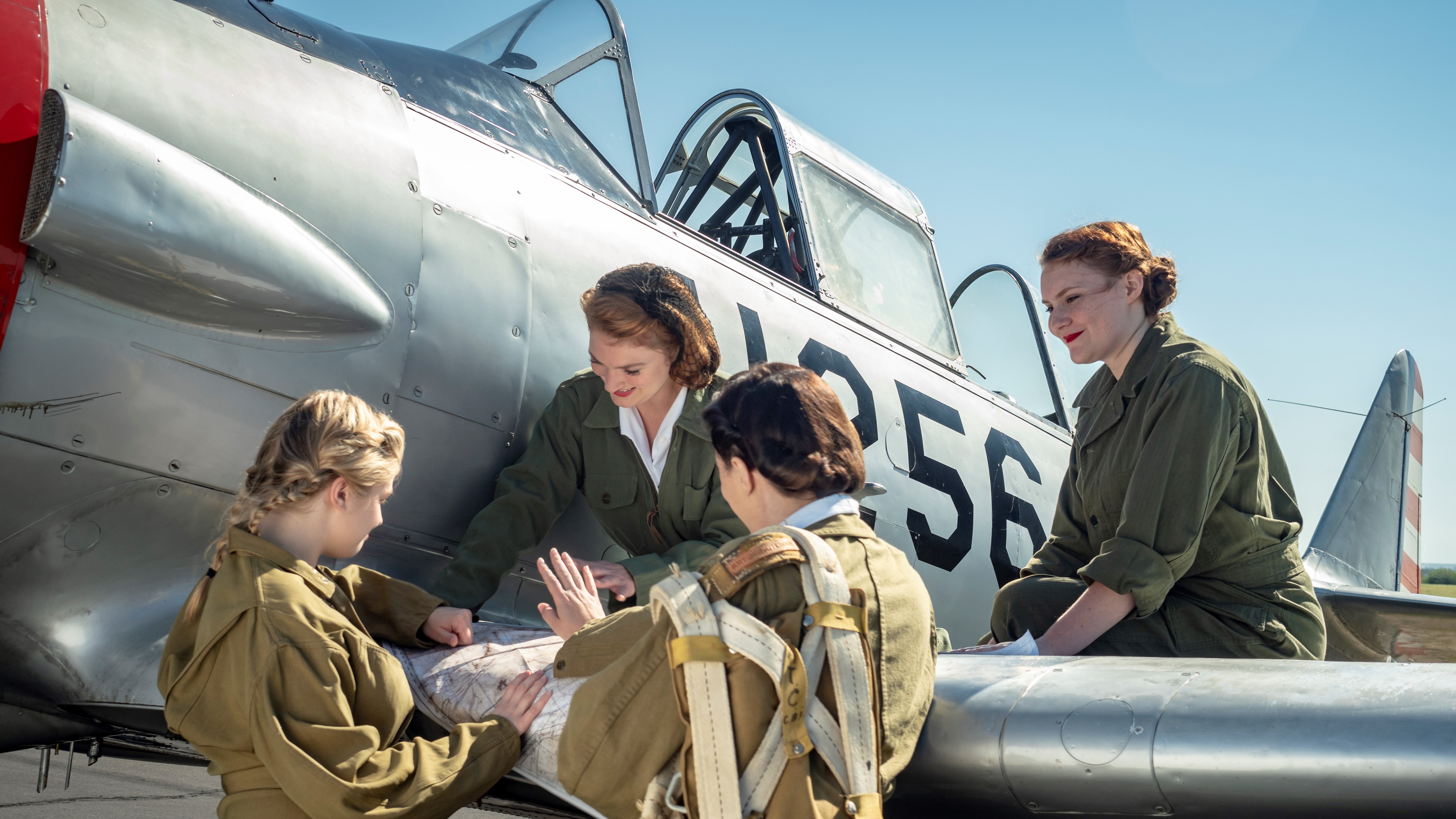 Women Airforce Service Pilots standing next to aircraft